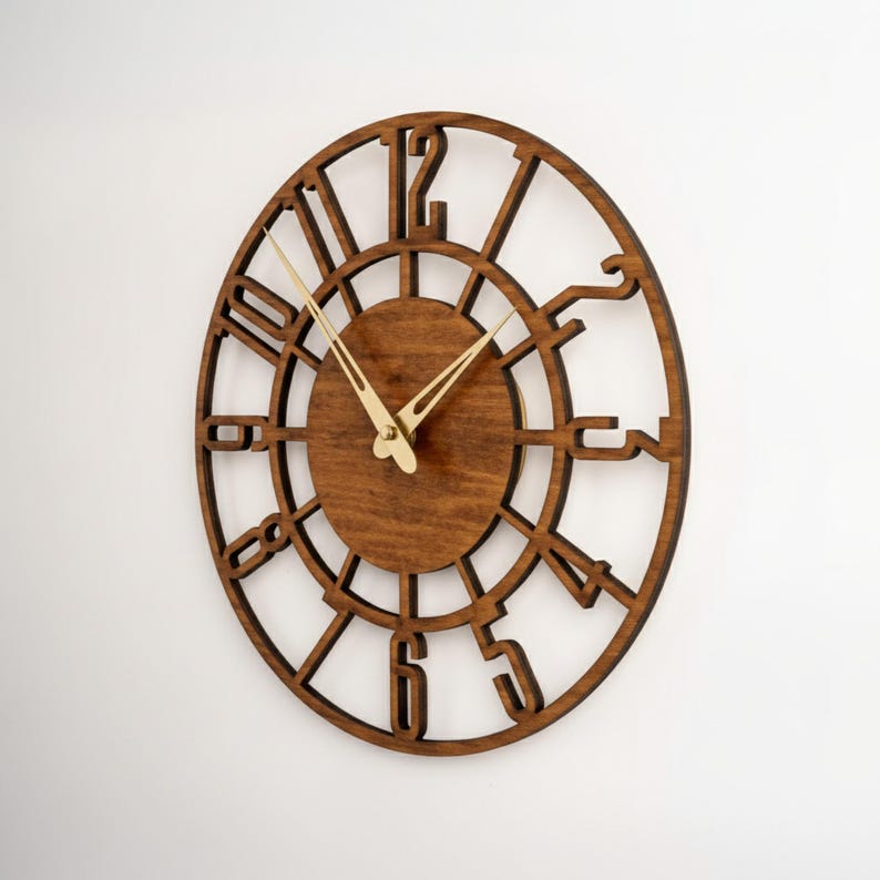Puede incluir: Un reloj de pared de madera con acabado marr&oacute;n oscuro. El reloj presenta un dise&ntilde;o circular con n&uacute;meros recortados y una esfera central. Las manecillas doradas indican la hora. El reloj est&aacute; montado en una pared blanca.
