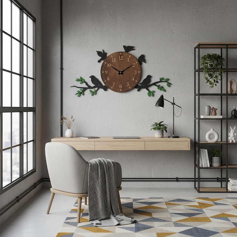 May include: A brown wooden wall clock with black hands and numbers, adorned with black bird silhouettes and green leaf accents. The clock is mounted on a gray wall above a wooden desk, creating a nature-inspired home decor theme.