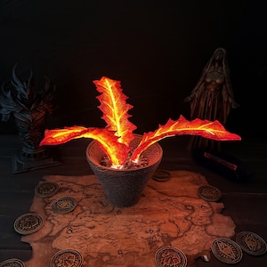 May include: A decorative fantasy scene featuring a glowing, fiery plant in a textured pot. The plant's leaves are a vibrant orange and red. The scene includes a map, coins, and statues, creating a mystical ambiance. The lighting is dim, enhancing the fiery glow.