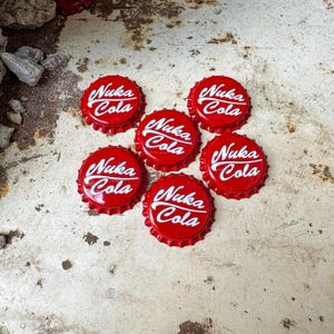 May include: Seven red bottle caps with white lettering that reads "Nuka Cola".