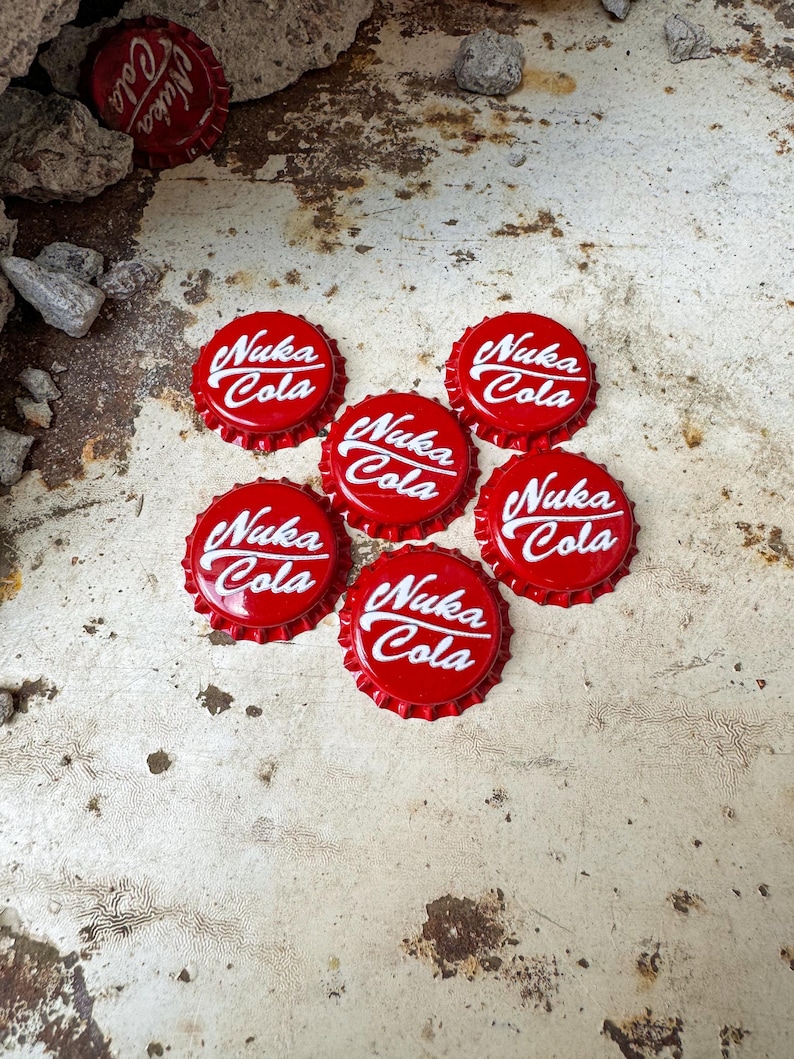 May include: Seven red bottle caps with white lettering that reads "Nuka Cola".