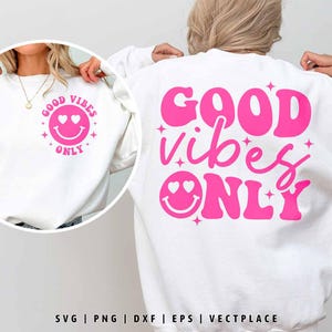Peut inclure: Sweat-shirt blanc avec un texte rose qui dit "GOOD vibes ONLY" et un smiley rose avec des cœurs pour les yeux.
