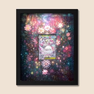 Może przedstawiać: Oprawiona grafika z kartą kolekcjonerską Pokémon na kwiatowym tle. Karta, wyśrodkowana w ramie, przedstawia postać z tekstem "Overflowing Wishes" i "Mega Symphonia". Rama jest czarna, a tło to kolorowy kwiatowy wzór.