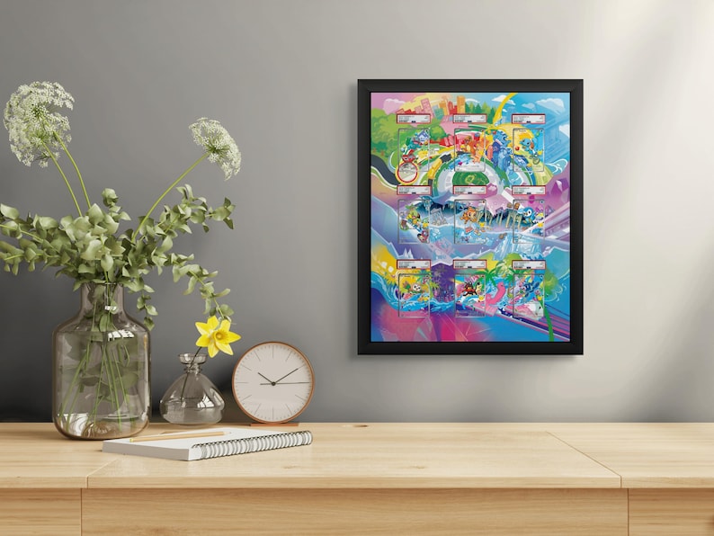 May include: A framed, colorful artwork with a black border hangs on a gray wall. The artwork features a vibrant, cartoonish design with various scenes and characters. A clear glass vase with flowers, a clock, and a notebook are on a wooden table.