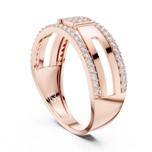 May include: Rose gold ring with a modern design. The ring features a rectangular top with a row of small, clear stones. Two parallel bands are set with small, clear stones. The ring has a unique, open design.