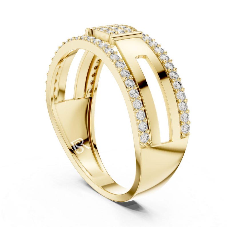 May include: A gold ring with a modern design. The ring features a rectangular top with small, clear stones and two parallel bands with additional stones. The ring has a unique open design with a polished finish.
