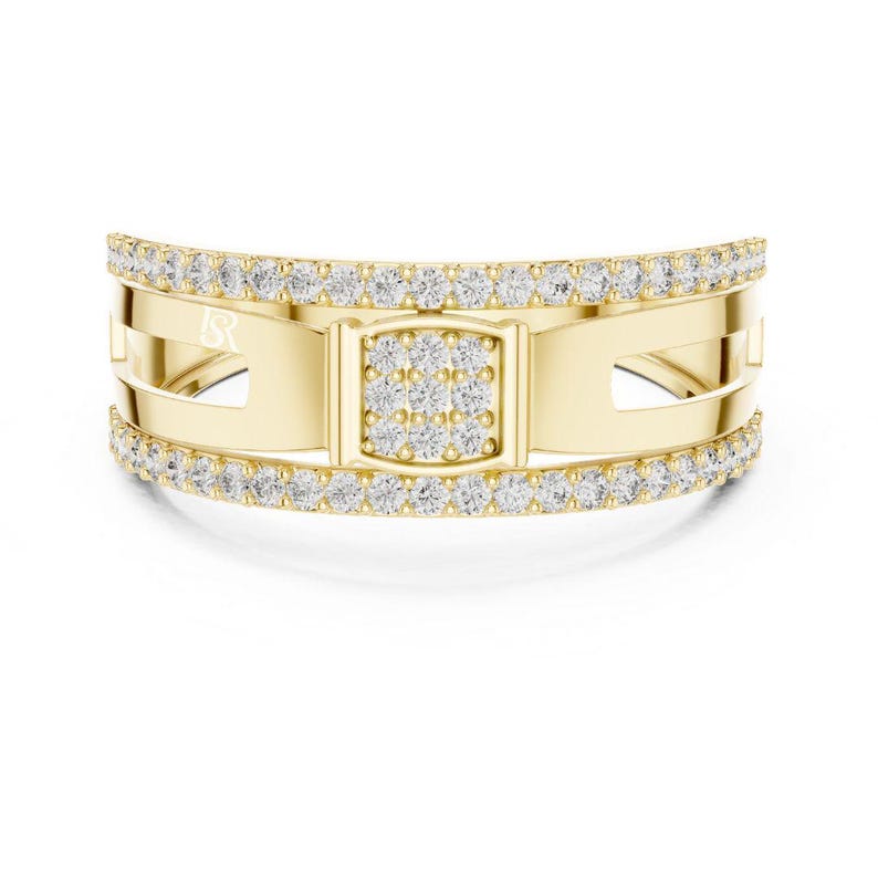 May include: A gold ring with a rectangular center section and a band of small, clear stones. The ring has a curved design with cut-out sections and a small logo on the side.