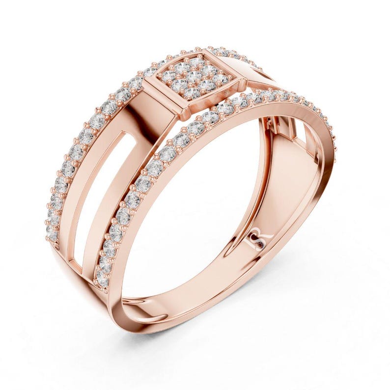 May include: Rose gold ring with a square center and a row of small, clear stones. The ring has a split band design with two parallel bars and a curved band. The ring is set against a white background.
