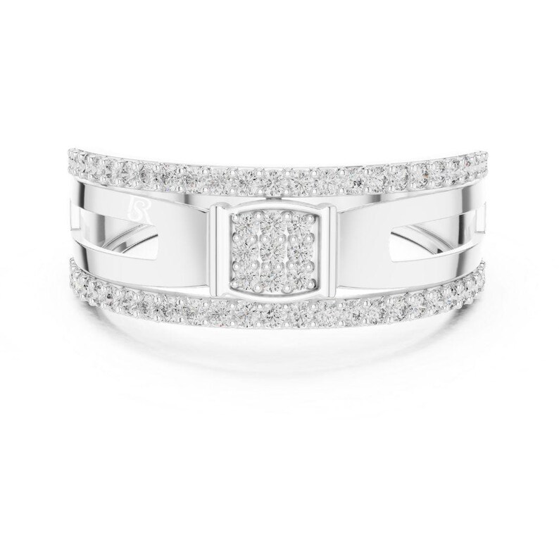 May include: A silver ring with a rectangular center section and a band of small, clear stones. The ring has a modern design with cut-out details and a curved shape. The ring is set against a white background.