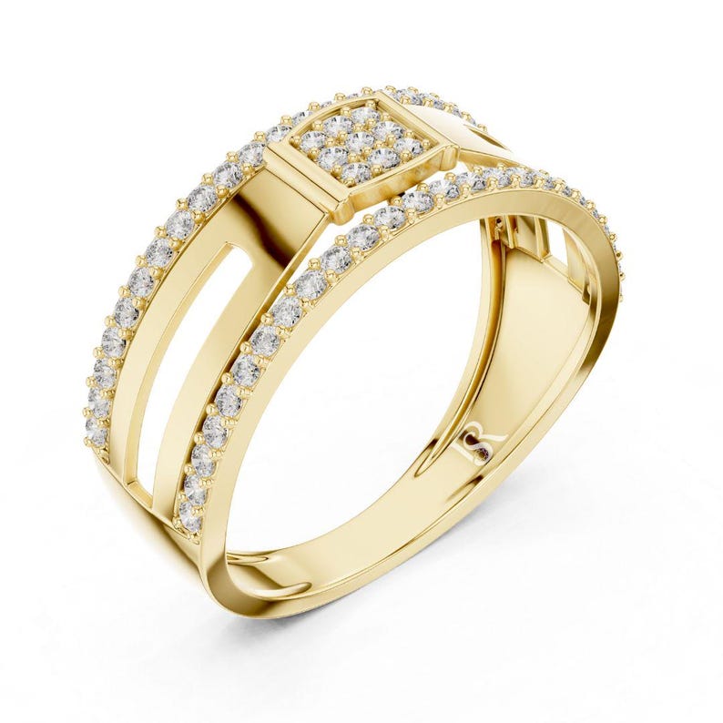 May include: A gold ring with a square center and two parallel bands. The ring is encrusted with small, clear gemstones. The band has a smooth, polished finish. The ring is set against a white background.