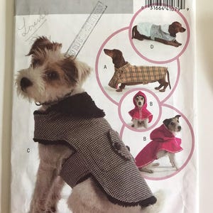 Può includere: Cartamodello Butterick B4885 per cappotti e mantelli per cani. Il modello include vari stili, come un cappotto a quadri, un mantello con cappuccio rosso e un cappotto pied-de-poule. La copertina del modello presenta un cane con un cappotto pied-de-poule.