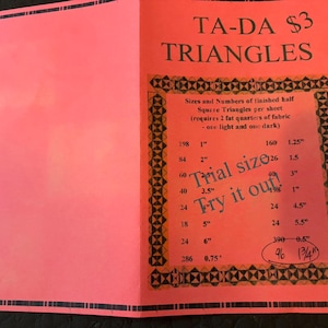 May include: A bright neon pink informational sheet titled TA-DA TRIANGLES. The document features a black geometric border and a printed table listing sizes and quantities of finished half square triangles, including a handwritten note Trial size Try it out!