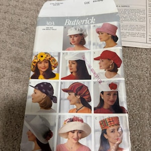 May include: A Butterick 303 sewing pattern envelope featuring illustrations of various hat styles including a sunflower print bucket hat, a red cap, a white cap with a red flower, a patterned bandana-style hat, and several wide-brimmed hats.