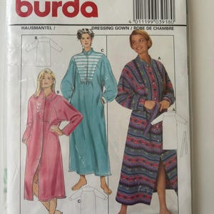 May include: A Burda sewing pattern envelope for a dressing gown, labelled 3918. The package displays illustrations of three different robe styles: a solid pink robe, a solid teal robe with a striped yoke, and a patterned robe with geometric designs.