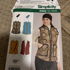 May include: A Simplicity 1499 sewing pattern envelope for a vest. The front displays illustrations of four vest variations in paisley, blue, yellow, and red, alongside a photograph of a person wearing the paisley vest with a black headband.