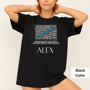 May include: Black t-shirt with the name "ALEX" in white, below a graphic of cybersecurity terms. The graphic includes words like "Information Security Analyst" and "Cybersecurity". The shirt is a solid black color.