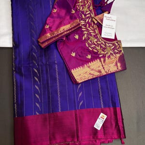 May include: A royal blue saree with vertical gold stripes and a wide magenta border, paired with a matching magenta blouse featuring gold floral embroidery and a tag reading Sheetal's FabFashion Jewelry & Sarees Boutique.
