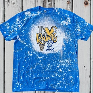 May include: A blue t-shirt with white bleach splatters and a yellow, black, and white graphic that says "LOVE RAMS".