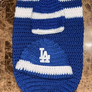 May include: A blue and white crocheted baby blanket with a matching blue and white crocheted hat. The hat has a white LA logo on the front.