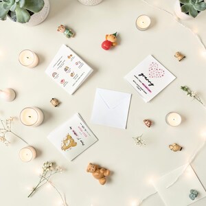 Puede incluir: Vista a&eacute;rea de tarjetas de felicitaci&oacute;n, velas y peque&ntilde;os adornos. Las tarjetas presentan texto e ilustraciones. Una tarjeta dice "Happy First Mother's Day Granny". Los adornos son de osos y otros animales.