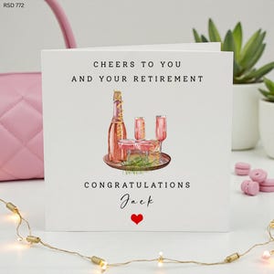 Puede incluir: Tarjeta de felicitación blanca con el texto "Cheers to You and Your Retirement" y "Congratulations Jack". La tarjeta presenta una ilustración de acuarela de una botella de champán, copas y un corazón rojo.