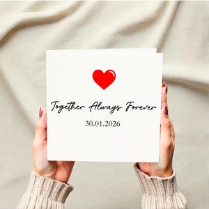 Może przedstawiać: Biała karta z czerwonym sercem i napisem "Together Always Forever" w eleganckiej czcionce. Data "30.01.2026" jest wydrukowana poniżej. Karta jest trzymana na neutralnym tle.