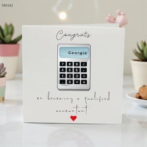 May include: White greeting card with the word "Congrats" and a calculator graphic with the name "Georgia" on the screen. The text "on becoming a qualified accountant" is below the calculator, with a red heart.