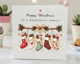 May include: A square white greeting card with the text Happy Christmas TO A WONDERFUL FAMILY. The design features a wooden branch with five hanging Christmas stockings, each with a name tag, decorated with pine, berries, and a central bow.