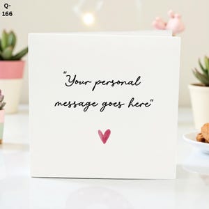 Może przedstawiać: Biała kartka z życzeniami z napisem "Your personal message goes here" czarnym pismem. Małe różowe serce znajduje się pod tekstem. Karta jest kwadratowa i stoi pionowo.