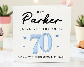 May include: A white birthday card with the name "Parker" in black script. The card features a light blue "70" and the text "Kick off the fun!" and "Have a 70th wonderful birthday!" with blue heart accents.