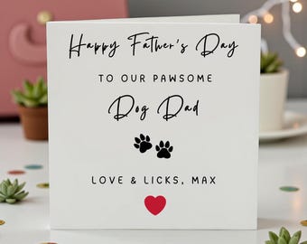 May include: A white Father's Day card with black script that reads "Happy Father's Day" and "To Our Pawsome Dog Dad." The card includes two black paw prints and a red heart. The text "Love & Licks, Max" is at the bottom.