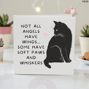 May include: A white square card featuring a black cat illustration and the text "NOT ALL ANGELS HAVE WINGS... SOME HAVE SOFT PAWS AND WHISKERS". Two pink hearts are above the cat.