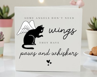 May include: A white square block with the text "SOME ANGELS DON'T NEED wings THEY HAVE paws and whiskers." A black cat with white angel wings is in the center. Two small black hearts are at the bottom.