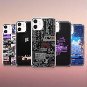 May include: A collection of five phone cases with various designs. One case features a collage of car images, while another has Japanese text. Other cases display car graphics and Japanese-inspired designs. The cases are clear with black borders.