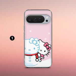 May include: A clear phone case featuring a pink background with white polka dots. The case has a cartoon illustration of Hello Kitty and a snowman. Hello Kitty is wearing a pink bow and the snowman has a blue bow and red scarf.