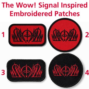 Op de afbeelding: Vier geborduurde patches genummerd van 1 tot 4, met de Wow!-signaalsequentie. Twee zijn rechthoekig en twee zijn rond. Patches 1 en 2 hebben een rode achtergrond met zwart borduurwerk, terwijl patches 3 en 4 een zwarte achtergrond met rood borduurwerk hebben.