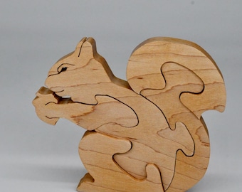 May include: A wooden squirrel puzzle with multiple interlocking pieces. The squirrel is in a sitting position with its tail curled behind it.
