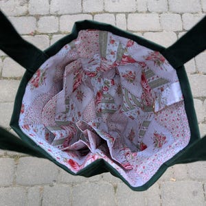 May include: A dark green tote bag with an open top, featuring a white interior lining decorated with a repeating pattern of pink roses, green leaves, and small floral sprigs. The bag includes multiple internal pockets along the sides.