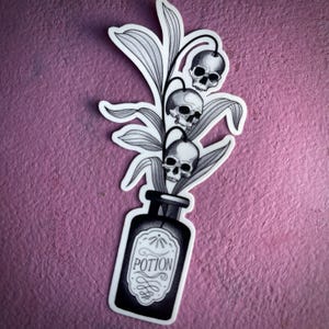 Peut inclure: Autocollant noir et blanc représentant une fiole de potion avec le mot "POTION" sur l'étiquette. La bouteille contient une plante avec trois fleurs en forme de crâne. L'autocollant a une bordure blanche.