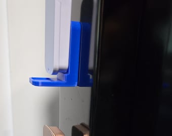 May include: Two wall-mounted holders, one with a white and blue design, the other with a gold and purple design. The holders are designed to hold small electronic devices. The holders are attached to a wall or door.