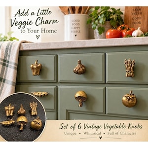 May include: A set of six gold-toned metal cabinet knobs shaped like vegetables, including a bell pepper, garlic bulb, asparagus bundle, pea pod, mushroom, and tomato. These decorative hardware pieces are shown installed on sage green drawers.