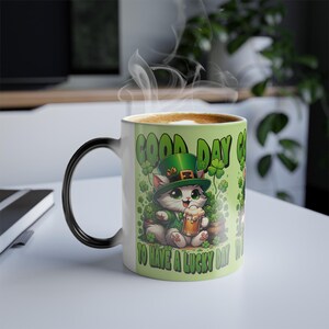Puede incluir: Una taza de cerámica blanca con un asa negra y el texto "But First, Coffee" en negro y negrita. La taza está sobre una superficie blanca. La taza mide aproximadamente 10 cm de alto.