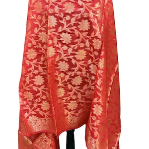 May include: A red and gold floral patterned shawl with a fringed edge.