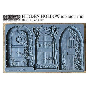 May include: A blue silicone mould featuring three detailed door designs. The mould is labelled "HIDDEN HOLLOW" and measures 15 cm by 25 cm. The doors include arched and wooden styles with intricate details.