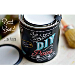 May include: A black paint can with a white lid. The can has a colourful design with the text "Debi's design diary DIY Paint".