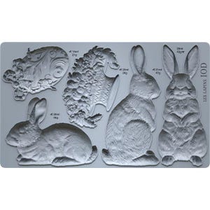 May include: A grey silicone mould featuring rabbit designs and floral embellishments. The mould includes detailed bunny figures in different poses, along with decorative floral elements. The text "LES LAPINS IOD" is printed on the right side.