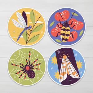 Può includere: Set di quattro sottobicchieri rotondi con illustrazioni di insetti. I disegni includono una libellula, uno scarabeo, un ragno e una falena. Ogni sottobicchiere ha un bordo bianco e uno sfondo colorato.