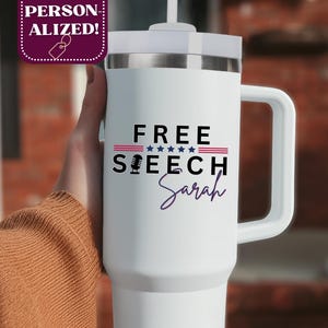 May include: White travel mug with a handle and a silver lid. The mug features the words "FREE SPEECH" above a microphone graphic and the name "Sarah" in a cursive font. The design includes red, white, and blue accents.