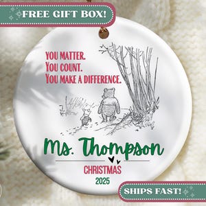 May include: A white ceramic Christmas ornament featuring a Winnie the Pooh illustration. The ornament includes the text "You Matter. You Count. You Make a Difference." and "Ms. Thompson Christmas 2025". A gold string is attached for hanging.