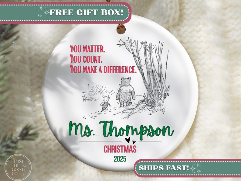 May include: A white ceramic Christmas ornament featuring a Winnie the Pooh illustration. The ornament includes the text "You Matter. You Count. You Make a Difference." and "Ms. Thompson Christmas 2025". A gold string is attached for hanging.